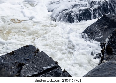 A mesmerizing shot of a wave breaking, capturing the intricate patterns and textures of the foamy white water as it crashes against the shoreline.