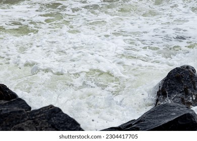 A mesmerizing shot of a wave breaking, capturing the intricate patterns and textures of the foamy white water as it crashes against the shoreline.