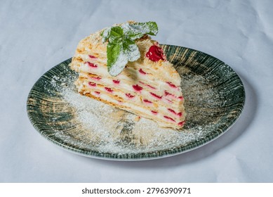 A mesmerizing slice of raspberry layered cake sits on a green rustic plate. Sweetness awaits.