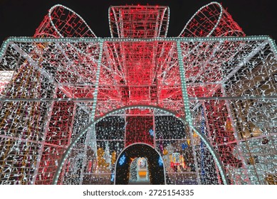 A mesmerizing structure of intertwined lights forms a tunnel with vibrant red and white hues. The intricate design creates a magical and immersive experience.