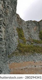A mesmerizing view of cliffs along the sandy beach of the Kuril Islands. The rugged rocks rise majestically from the shoreline, creating a stunning backdrop, embodying the beauty and serenity of nature's untouched landscape.