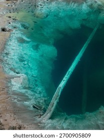 A mesmerizing view of a geothermal hot spring with crystal clear turquoise water and mineral-rich formations.