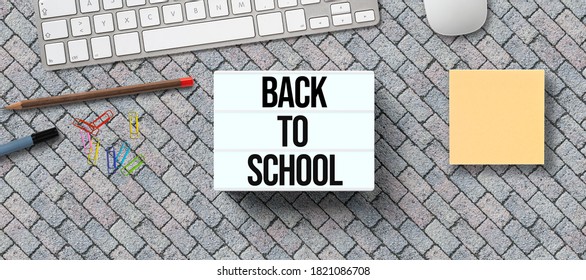 message BACK TO SCHOOL on lightbox with utensils on stone pavement background