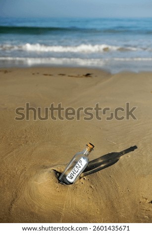 Message in a bottle on the sand of a beach with waves and the horizon. When? When will it happen? Concept of the passage of time. The word 