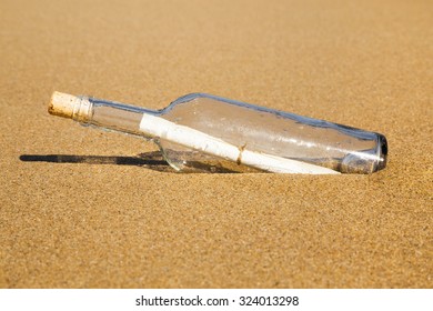 Message in a clear glass corked bottle partially buried in beach sand conceptual of a love letter from a sweetheart or plea for help form a shipwreck or marooned sailor carried ashore by the tides. - Shutterstock ID 324013298