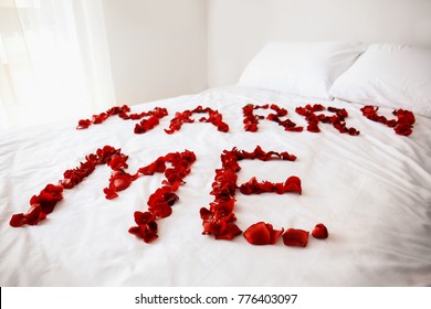 Message MARRY ME Made Of Rose Petals On Bed In Room