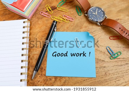 Message on Good Work written on a piece of paper, with a pen, paper clips, men wristwatch and notebook on the wooden table 
