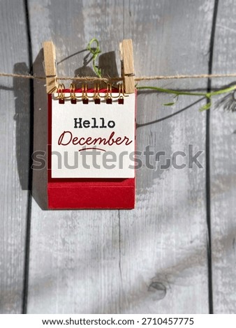 “Hello December” message on note pad clipped to a string with copy space background. Perfect for Christmas season promotions, winter greetings, holiday announcements, and festive layouts.