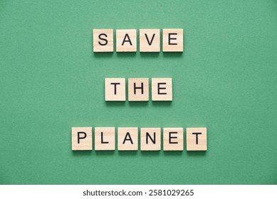 Message representing the concept of environmental awareness and concern for the future of the Earth, wooden pieces with letters form, on a green background, the text Save the planet.