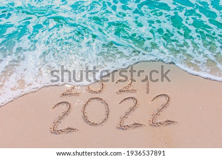 Message Year 2021 replaced by 2022 written on beach sand background. Good bye 2021 hello to 2022 happy New Year coming concept.
