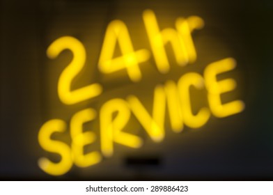 Message in yellow neon on black background for 24 hour service