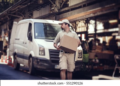 Messenger Delivering Parcel, Walking In Street Next To His Van