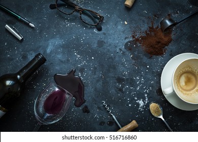 Messy bar table - empty coffee cup, spilled wine, glasses and pen. Writer's desk scenery after late night work concept. Flat lay layout captured from above (top view). Background with free text space.