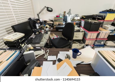 Messy business office with piles of files and disorganized clutter.