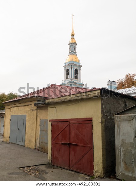 Messy car garages with St. Nicholas Naval\
Cathedral bell tower at\
background