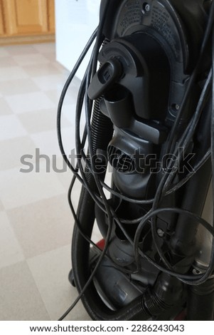 Messy cord on the vacuum cleaner. The wrong way to put away the power cord. Tangled mess.