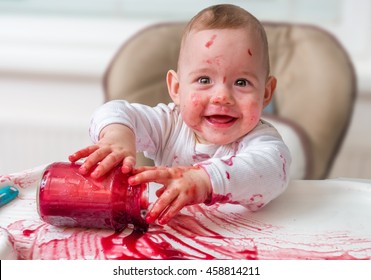 Messy And Dirty Baby Is Eating Snack With Hands.