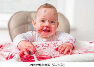 Messy And Dirty Baby Is Eating Snack With Hands.