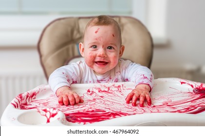 Messy And Dirty Baby Is Eating Snack With Hands.