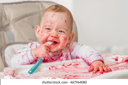 Messy And Dirty Baby Is Eating From Spoon.