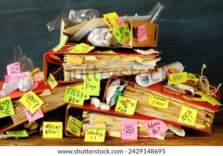 Messy file folder,sticky notes and old papers on a cluttered , chaotic office desk. Red tape, bureaucracy,overworked,burnout,exploitation,messy office and chaotic business concept.