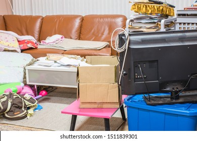 Messy Home In Living Room With Cloth, Book, Toy, Box And Sofa.