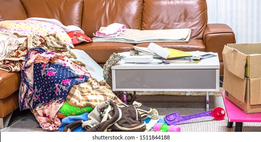 Messy Home In Living Room With Cloth, Book, Toy, Box And Sofa.