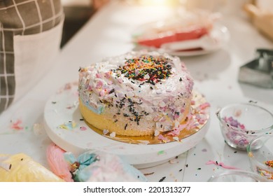 Messy Kitchen With Homemade Birthday Cake Made From Kids. Kitchen With Ingredients For Baking On Working Table. Messy Table Full With Pastries Items And Ingredients.