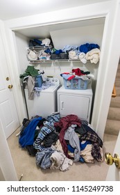 Messy Laundry Room Vertical View With Piles Of Clothes Needing To Be Washed.  