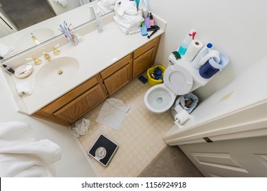 Messy Little Half Bathroom With Dirty Towels And Cleaning Clutter.  