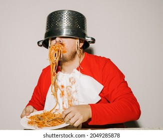 Messy Man Eating Pasta With Sauce. He Uses A Colander As A Hat And A Napkin As A Bib.