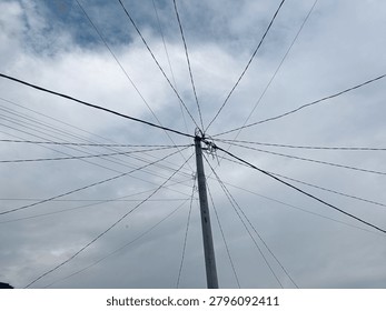 Messy network of internet data cables and overhead power lines radiating from a single street pole