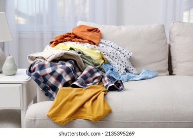 Messy Pile Of Dirty Clothes On Sofa In Living Room. Tidying Up Method