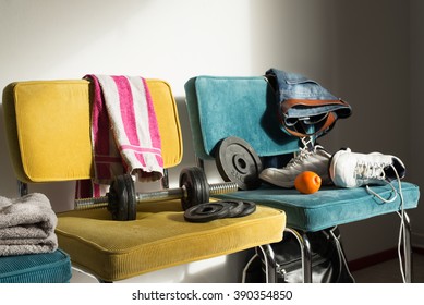 Messy Room Of A Boy Or Teenager Being Active. Chaotic Gym Or Fitness Interior. Chairs With Jeans, Towels, Sneakers And Dumbbells.