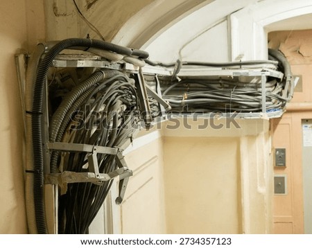 Messy tangle of electrical cables and conduits in an old building interior wall