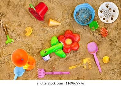 Messy Toys In Sand On Playpit. Top View. Playthings In Sand-pit, Overhead Shot. Sandbox With Baubles. Moulding Sand Quarry With Colorful Gimcrackery. Knick-knackery In Gravel. Sundry Nugae In Greva. 