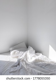 Messy Unmade Bed With All White Sheets In White Bedroom With Sun Shining In