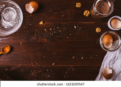 Messy Wooden Kitchen Table With Crumbles, Ingredients And Utensils For Cooking Pastry, Overhead View.