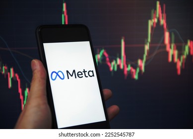 META logo on smartphone screen with hand hold and crypto currency or stocks graph charge trading screen on background. New facebook company logo meta metaverse.