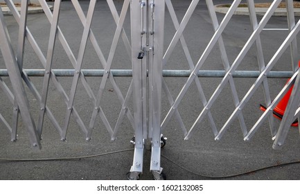 Metal Accordion Gate With Small Padlock And Orange Safety Cones At Construction Site.