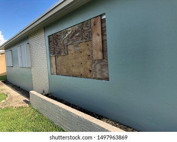 Metal Accordion Shutters A And Old Wooden Shutter Protect A Home’s Windows From A Coming Hurricane.