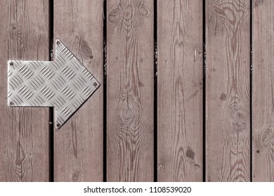 Metal arrow sign on wooden texture. Right arrow sign on wooden floor, wood background made of planks with arrow sign screwed to the surface. Go to the right. Go to the left. 