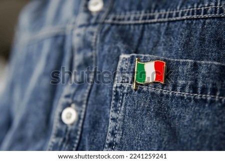 Metal badge with the flag of Italy is pinned on blue jeans jacket. Italy patriotism concept. Independence Day Holiday in Italy.