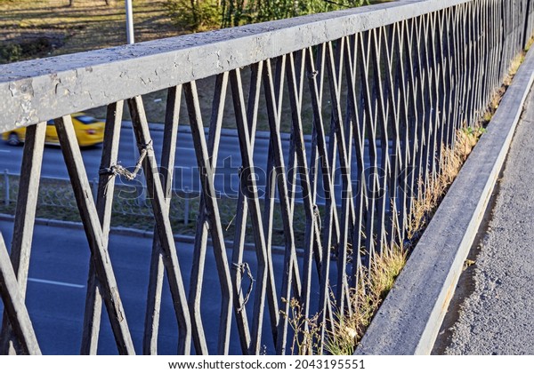 Metal barrier on a pedestrian bridge over the\
motorway on an autumn sunny\
day