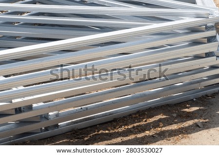 Metal beams stack darkly, gleaming under dim light. Rows of steel intersect with sharp angles and shadowed depth. Industrial decay feels heavy, yet orderly in its disarray. Ideal for construction