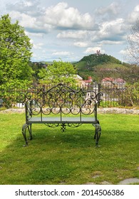 Metal Bench With Ornaments In Garden With The Beautiful View Of Green Hill With Historical Medieval Church On The Top. Old Mining Town Of Banska Stiavnica In Slovakia.