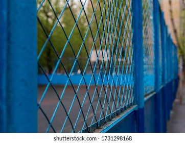Metal Blue Mesh Wire Fence With Blurry Background Of An Empty Basketball Court. Sport. Pandemic. Panorama.