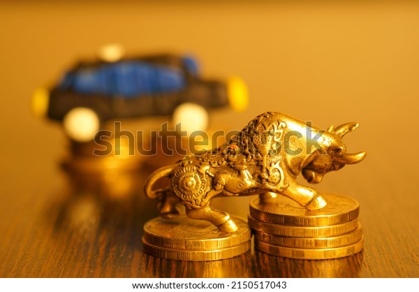 A\
metal bull with coins on the background of a toy\
car.