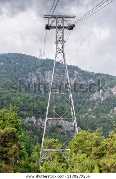 metal cable car support on the slope of Tahtalı\
mountain, against the backdrop of mountains and pine forest, Kemer,\
Turkey