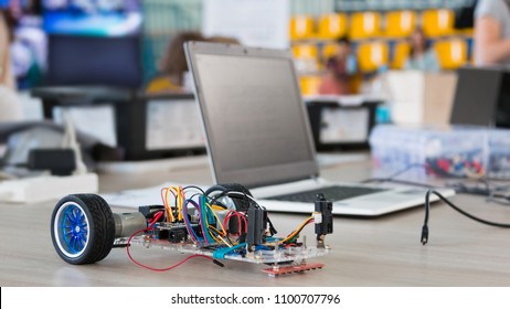 A Metal Car Robot And An Electronic Board That Can Be Programmed. Robotics And Electronics. Laboratory. Mathematics, Engineering, Science, Technology, Computer Code. STEM Education. 